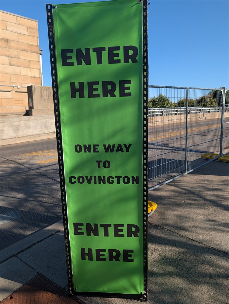 Green banner indicating one-way pedestrian entry to Covington across the Roebling Bridge walkway